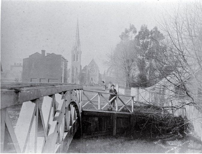 A man stands beside the Worcester Street Bridge : in background is the Cathedral, at left the Providential Society building. A man stands beside the Worcester Street Bridge : in background is the Cathedral, at left the Providential Society building.