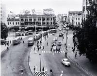 Cars and buses in Cathedral Square : view looking up Colombo Street, with the Colonial Mutual Life building behind the Cathedral [Apr. 1964]