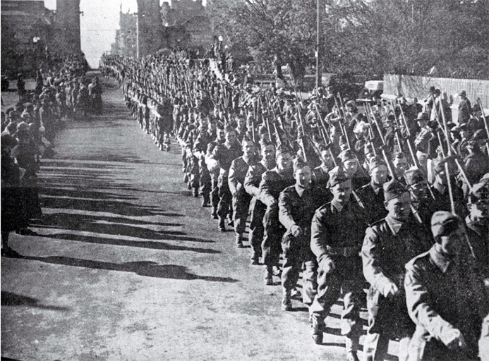 Second echelon of New Zealand Expeditionary Forces march west along Cashel Street, under the Bridge of Remembrance