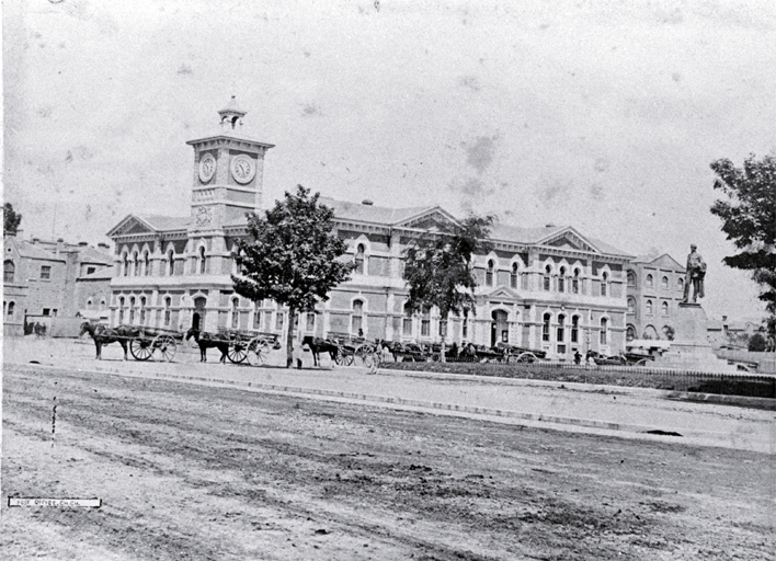 Delivery carts in Cathedral Square between the Godley statue & the Post Office, originally the Government Buildings, Christchurch. Delivery carts in Cathedral Square between the Godley statue & the Post Office, originally the Government Buildings, Christchurch.