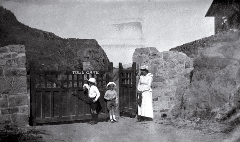 A woman with children stands outside the toll-gate to the Summit Road leading past the Sign of the Kiwi, Port Hills, Christchurch A woman with children stands outside the toll-gate to the Summit Road leading past the Sign of the Kiwi, Port Hills, Christchurch