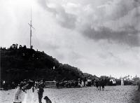 Children surround the donkey pen below the mast and yard-arm, Sumner beach, Christchurch