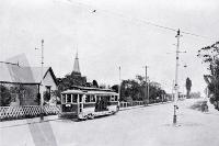 An electric tram on Harewood Road at the intersection with the Main North Road, looking up from Papanui