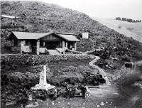 A car and excursionists in front of the Sign of the Kiwi, Dyers Pass, Summit Road, Christchurch