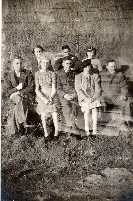 Mixed group some in uniform on banks of river next to fence Mixed group some in uniform on banks of river next to fence