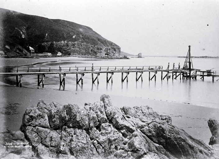 Construction of the Sumner Pier, Christchurch : looking from Cave Rock past the Sumner Hotel to Clifton Spur and Shag Rock. Construction of the Sumner Pier, Christchurch : looking from Cave Rock past the Sumner Hotel to Clifton Spur and Shag Rock.