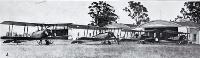 The New Zealand air arm of defence : Avro 504K aeroplanes lined up outside hangars.