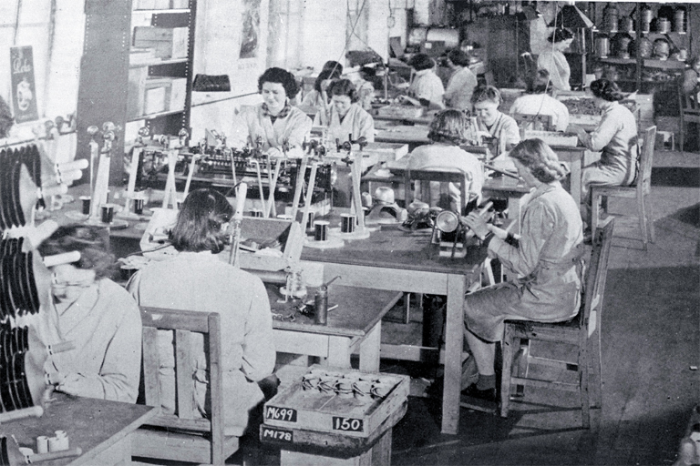 Girls in a small workroom engaged on assembly work Girls in a small workroom engaged on assembly work